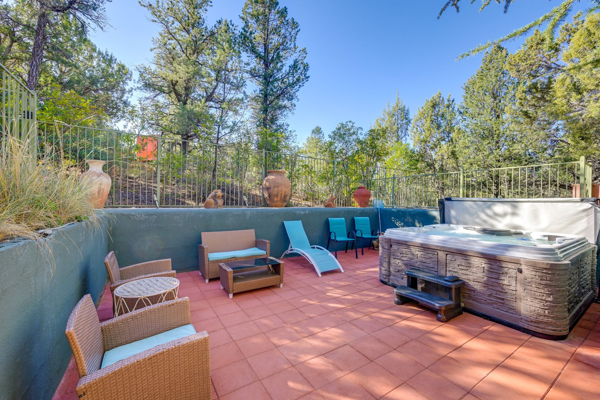 Private hot tub and lounge chairs on red-tiled patio surrounded by trees